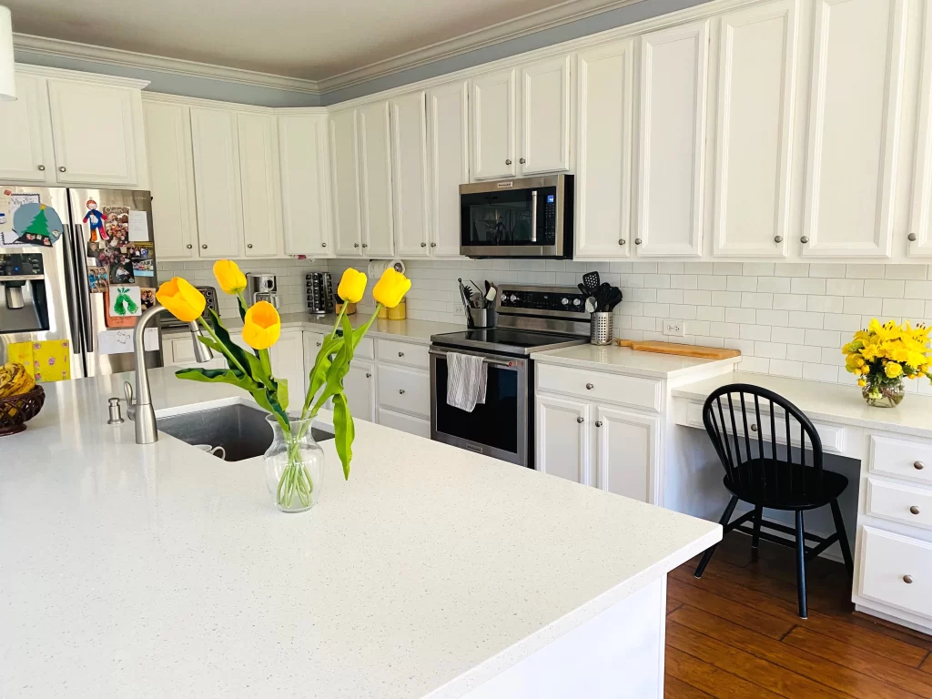 A photo of a kitchen with sparkling white quartz countertops. The countertops are a bright white color with small, sparkling speckles, and they contrast nicely with the dark gray cabinets and stainless steel appliances. The kitchen also has a large island with a breakfast bar, which provides additional counter space and seating. The overall effect is a bright and airy kitchen that is both stylish and functional.